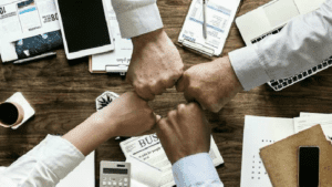 four people fist bumping in agreement over a desk