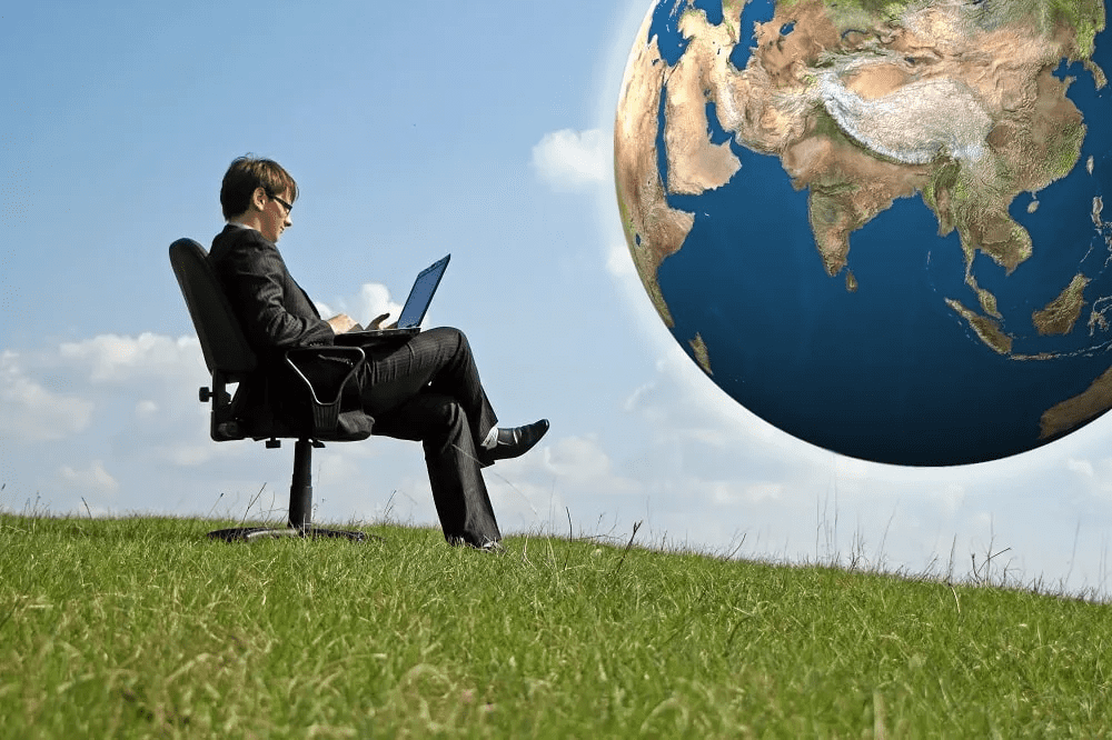 man sitting at laptop in front of image of a globe