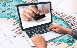 A laptop on a desk and pen, accompanied by an a person attempting to search for startup tips for virtual business