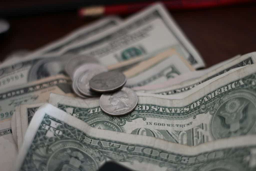 Close-up of U.S. dollar bills and coins, representing the cost to trademark a business name​