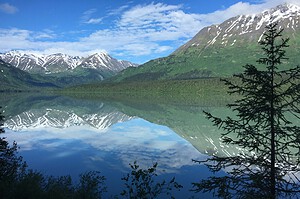 Snow-capped Alaska mountains reflected in a still lake