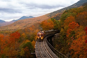 Train crossing a trestle through fall foliage in the New Hampshire mountains